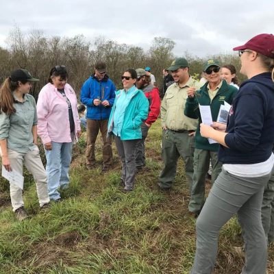 Heartland_Partners A group of people listen to a women describe the invasive properties of a new invasive herbaceous plant found in the area.