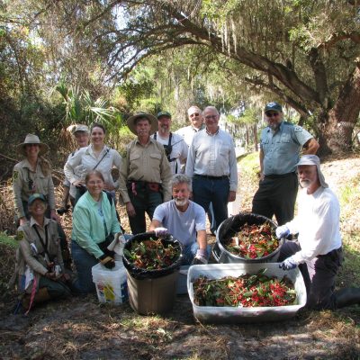 heartland_at work A group of people pose for a group photo while displaying the large quantity of coral ardisia they pulled that morning as part of an invasive species volunteer day.