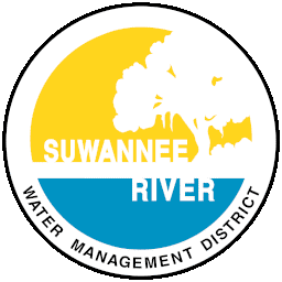 Suwannee River Water Management District Logo contains yellow upper half circle and blue lower half circle with a white tree silhouette and Suwannee River written in white, all encircled by a blue ring and the words "Water Management District" below.